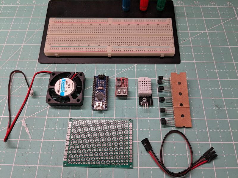 Arduino project components laid out on a cutting mat: a breadboard, Arduino Nano, DHT22 sensor, cooling fan, USB power module, transistors, and a perfboard