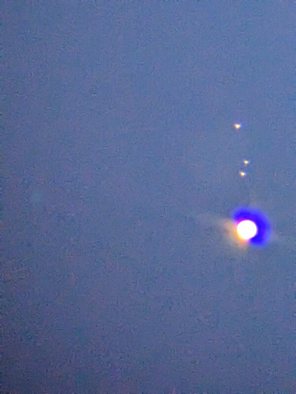 Jupiter as a bright point of light with several of its moons visible as faint points nearby
