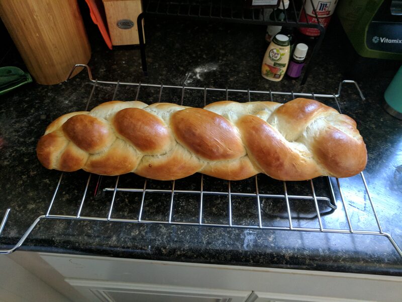 The same braided loaf, baked golden brown, cooling on a rack