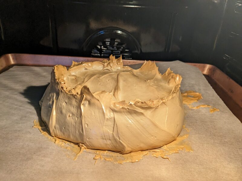 A caramel-colored pavlova, baked into a rustic nest shape on parchment paper