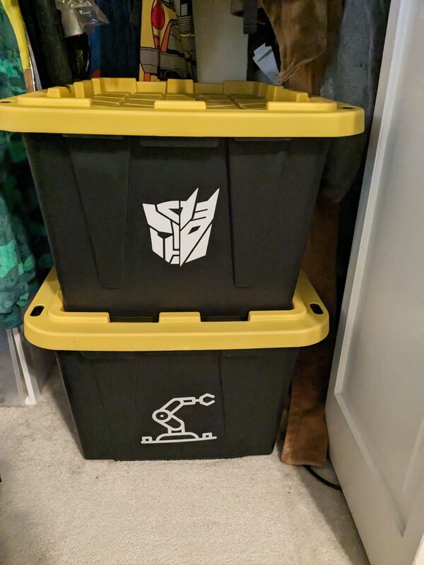 Two storage bins with vinyl decals - a Transformers Autobot/Decepticon emblem and a robotic arm icon