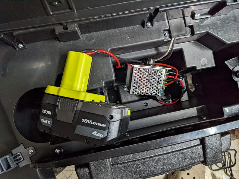 Inside a Power Wheels Jeep's battery compartment, showing a Ryobi 18V 4Ah lithium battery wired to a PWM speed controller module