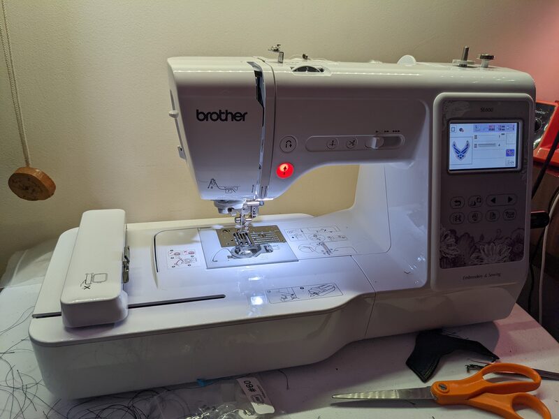 The Brother SE600 embroidery machine mid-stitch on an Air Force wings design