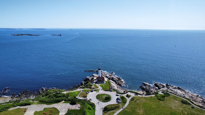 An aerial photo of a lighthouse on a rocky coastline, taken with a DJI camera drone