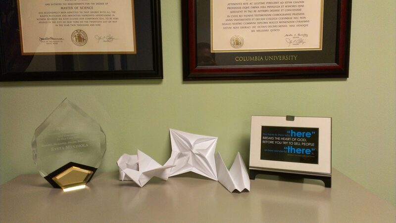White origami pieces I made for my wife while we were dating, displayed on her desk alongside her diplomas and an award
