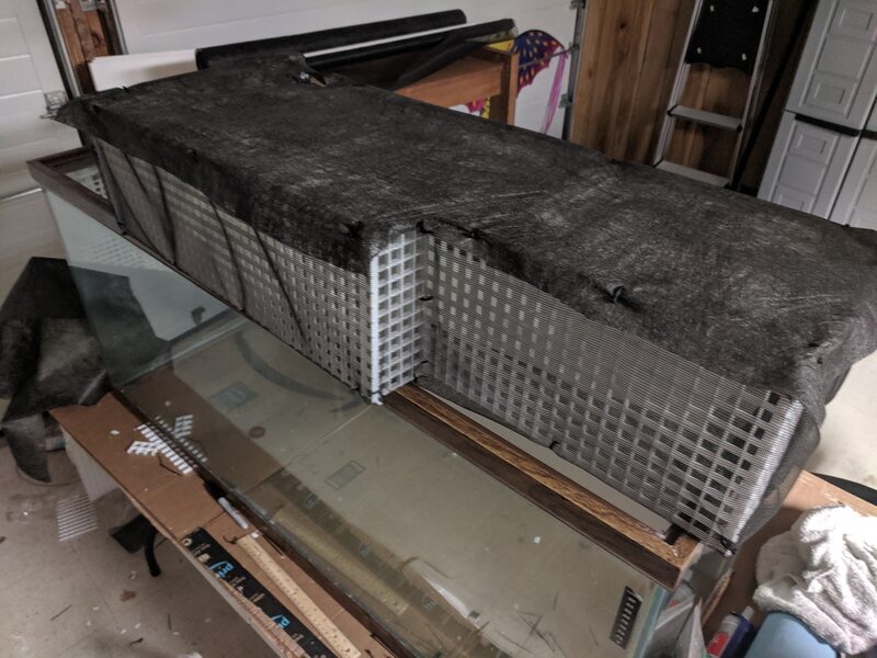 A mesh screen top being fitted over the tank, same day