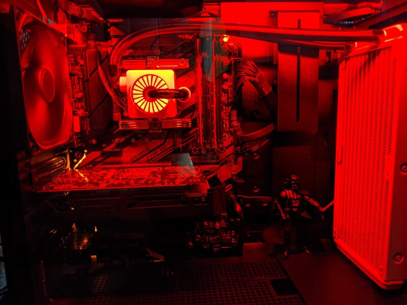 Inside the same PC build bathed entirely in red LED light, with a Darth Vader figure standing next to the radiator